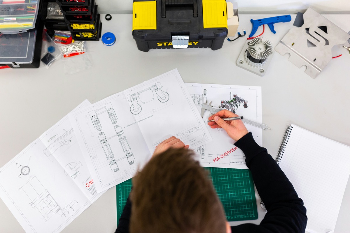 A drafter working on technical drawings at a desk