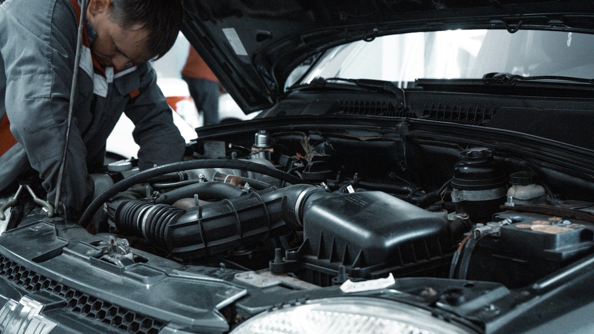 A mechanic working under the bonnet of a car